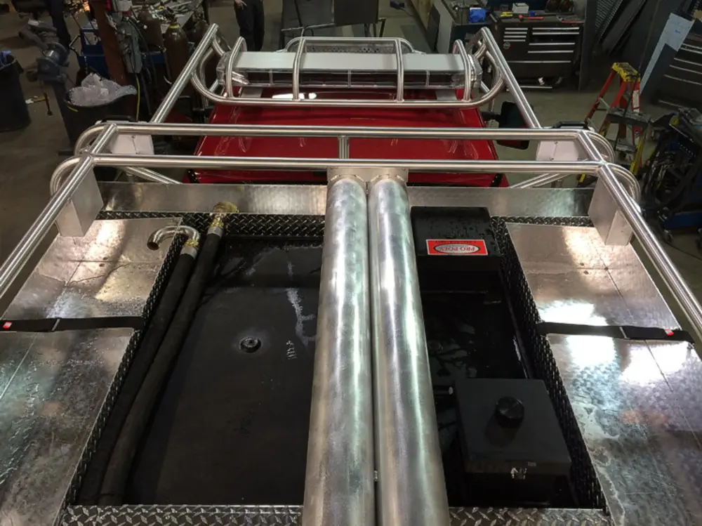 Exterior view of small fire truck showing cab, body compartments, and wheel/tire area.