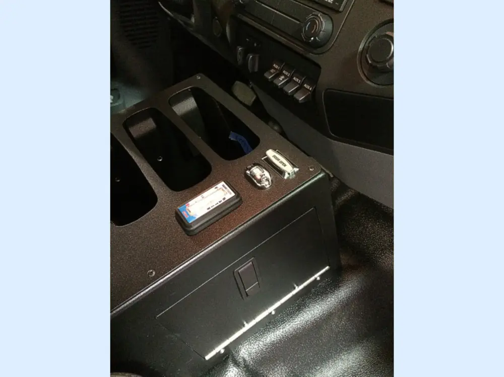 Exterior view of small fire truck showing cab, body compartments, and wheel/tire area.