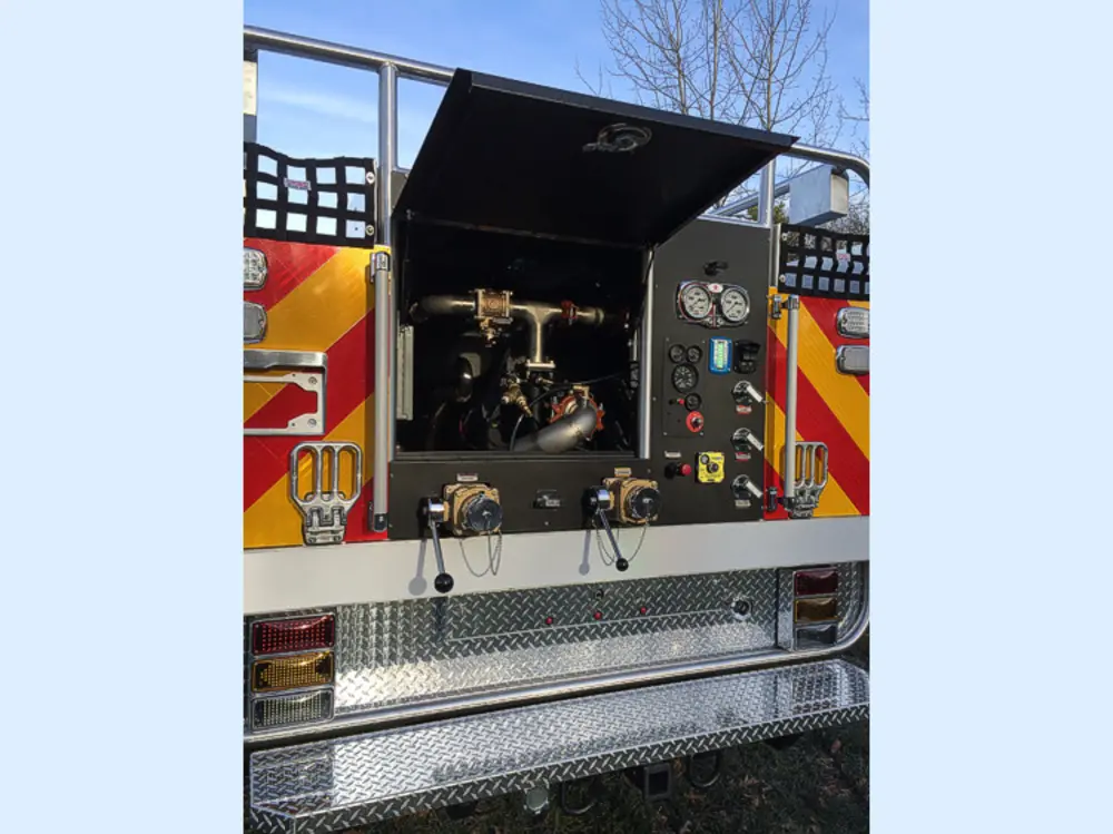 Exterior view of small fire truck showing cab, body compartments, and wheel/tire area.