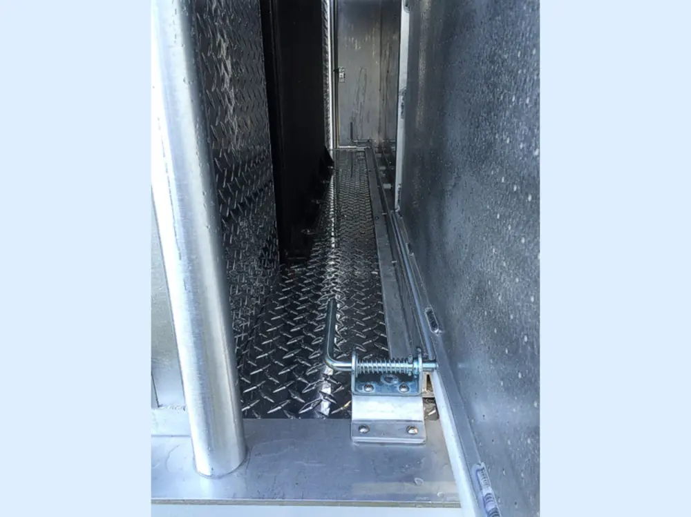 Exterior view of small fire truck showing cab, body compartments, and wheel/tire area.