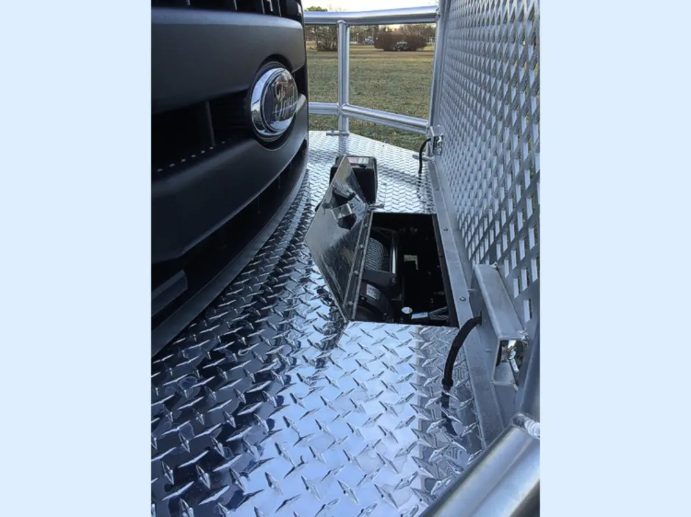 Exterior view of small fire truck showing cab, body compartments, and wheel/tire area.