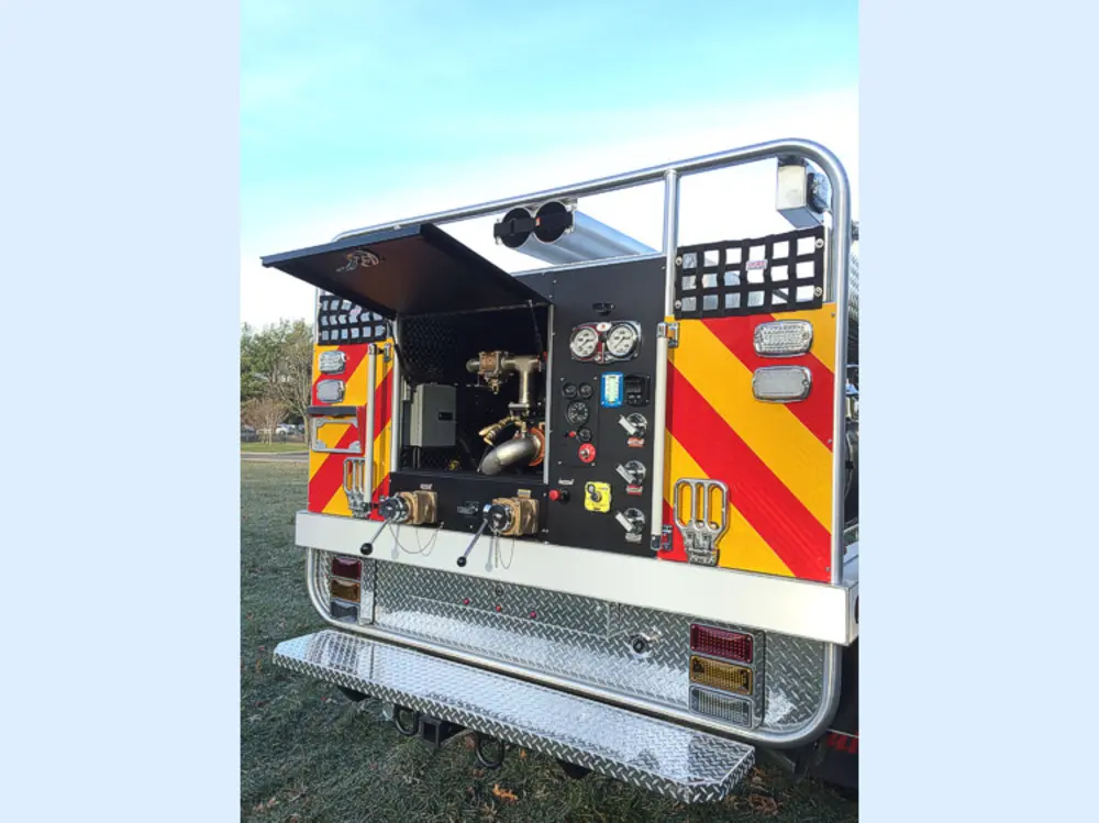 Exterior view of small fire truck showing cab, body compartments, and wheel/tire area.