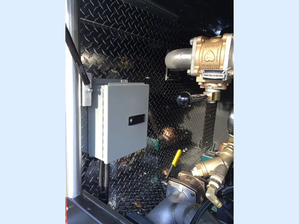 Exterior view of small fire truck showing cab, body compartments, and wheel/tire area.