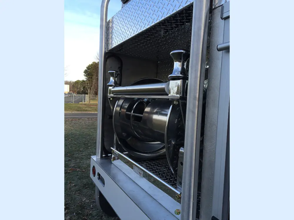 Exterior view of small fire truck showing cab, body compartments, and wheel/tire area.
