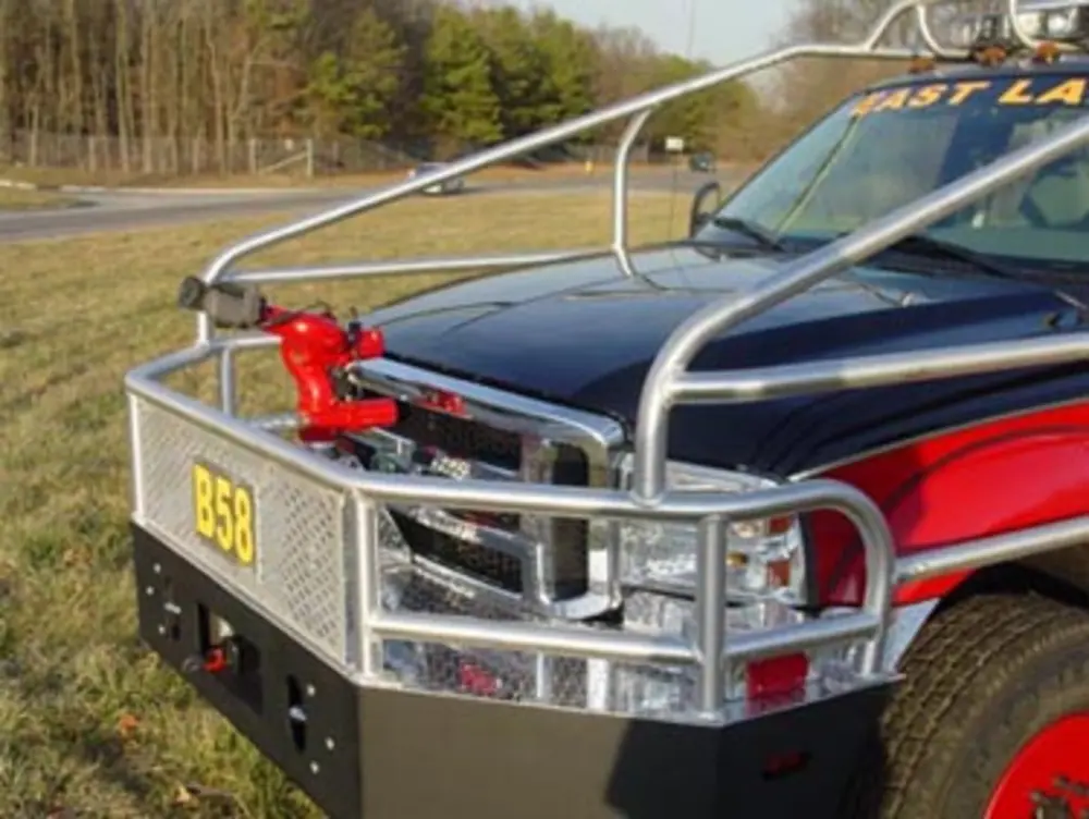 Exterior view of small fire truck showing cab, body compartments, and wheel/tire area.