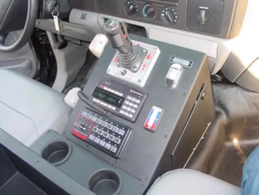 Exterior view of small fire truck showing cab, body compartments, and wheel/tire area.