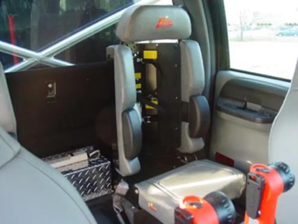 Exterior view of small fire truck showing cab, body compartments, and wheel/tire area.