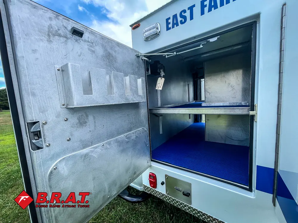 Open side compartment with shelf and blue floor mat.