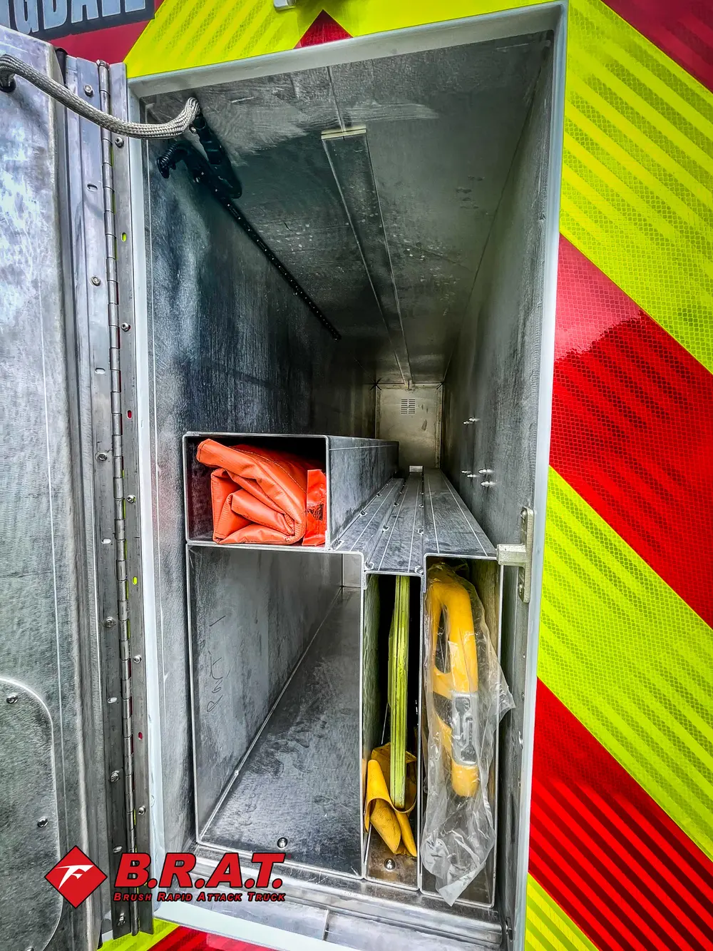 Inside narrow rear compartment with orange hose and shelf cubby.