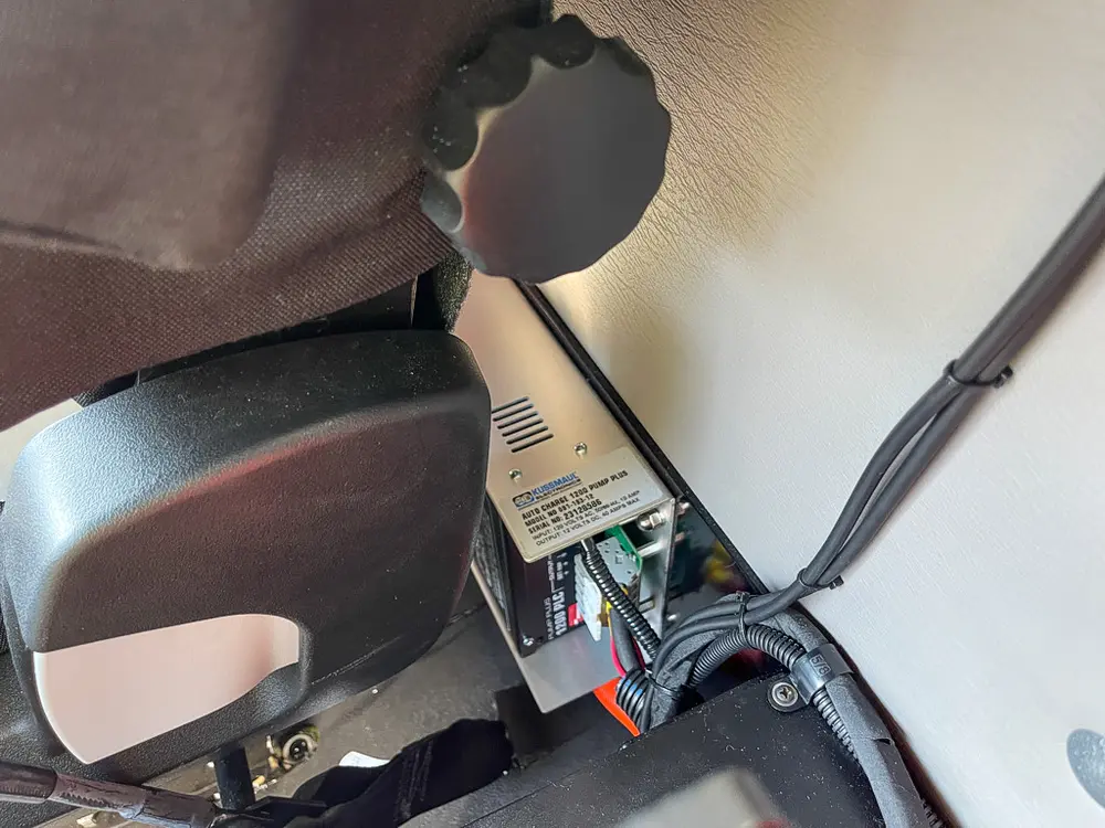 Footwell and wiring harness near seat base and pedals.