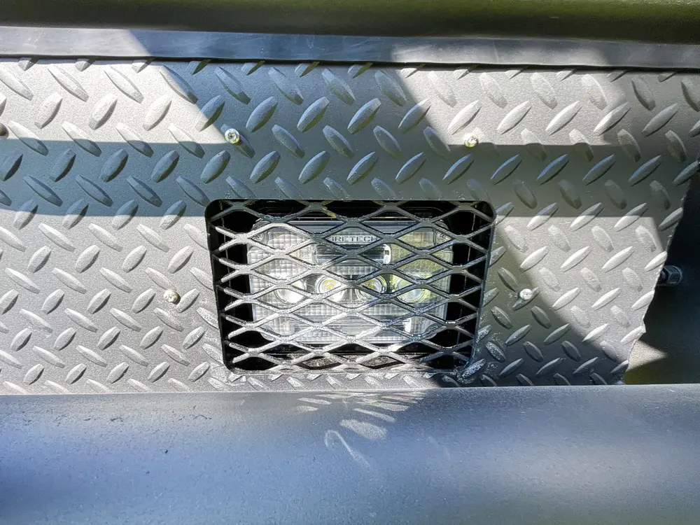 Front grille mesh and diamond-plate bumper close-up.