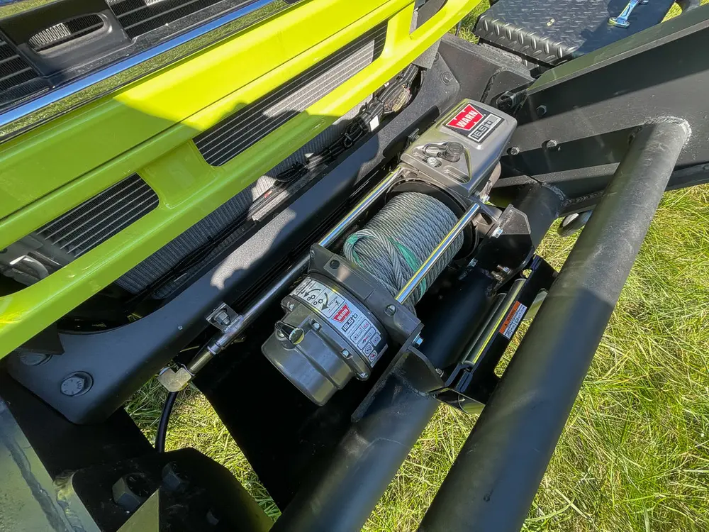 Hydraulic or pump hardware mounted behind bumper guard.