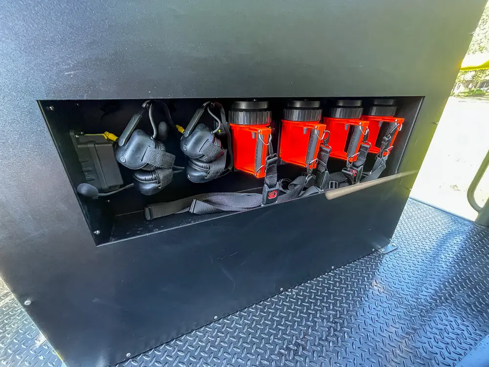 Open rear shelf compartment holding red nozzle fittings.