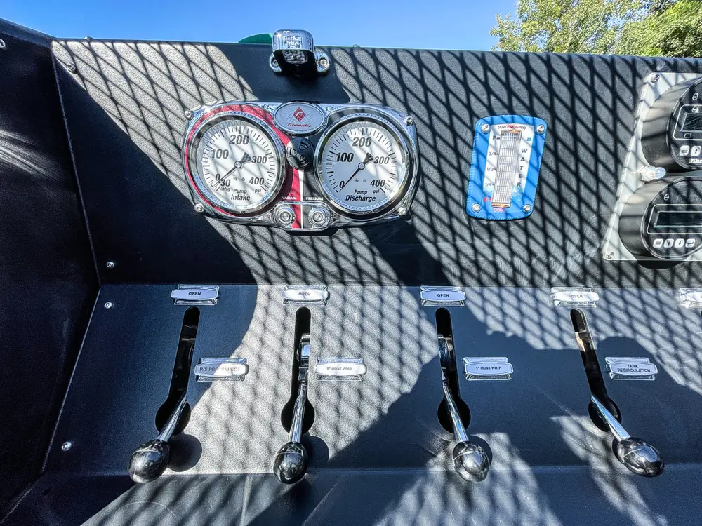 Pump gauges and valves close-up behind metal mesh cover.