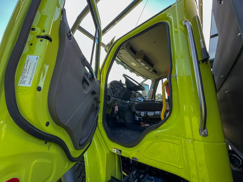 Open cab door revealing gray front seats and controls.
