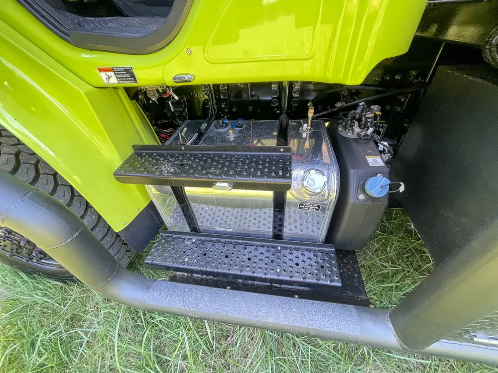 Battery and cylinder hardware mounted behind cab step.