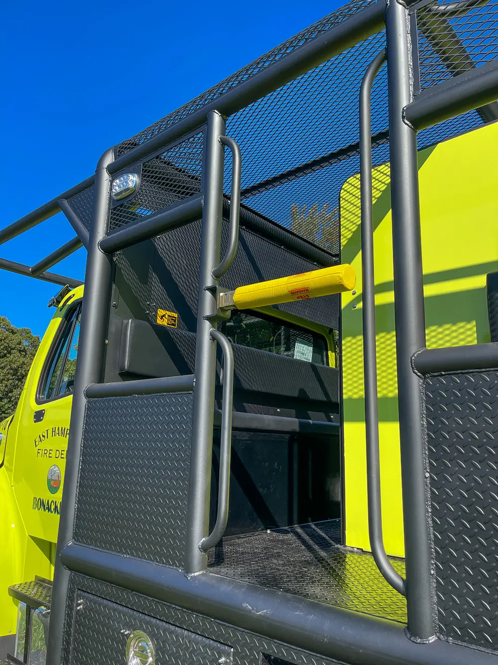 Rear side ladder and yellow handhold by cage rail.