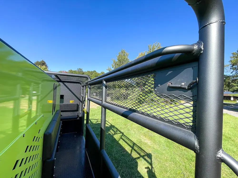 Narrow side walkway beside tank with cage rail overhead.