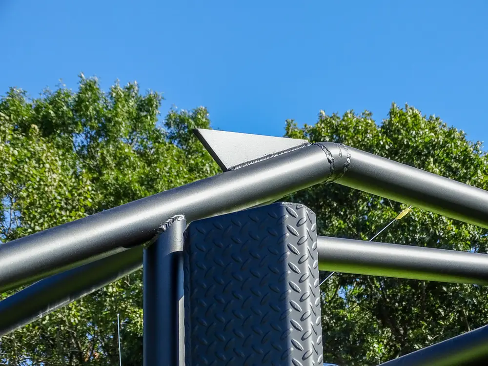Upper cage rail and light mast against blue sky.