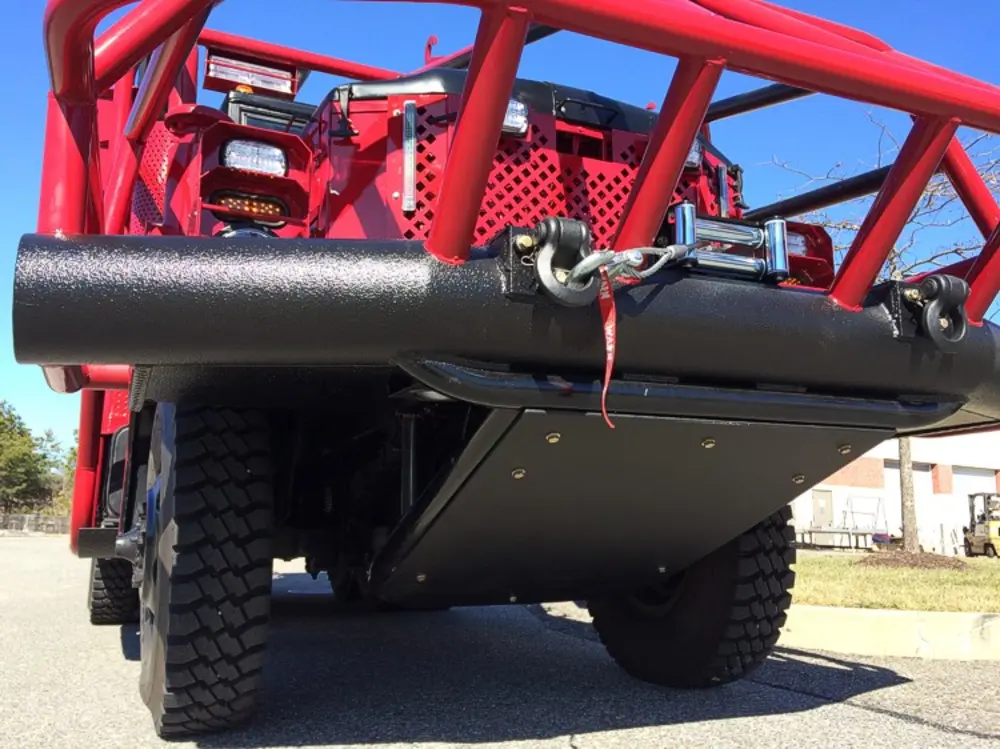 Exterior view of small fire truck showing cab, body compartments, and wheel/tire area.