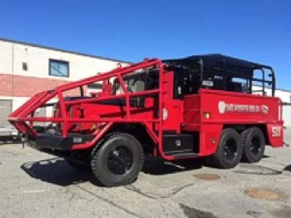 Exterior view of small fire truck showing cab, body compartments, and wheel/tire area.