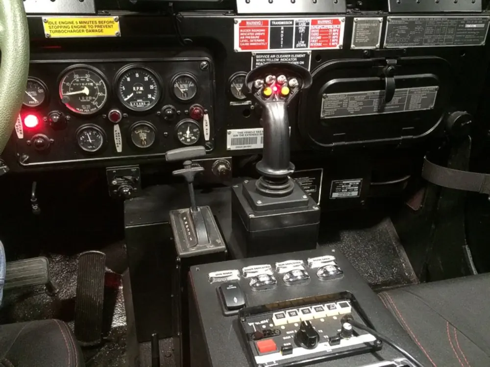 Exterior view of small fire truck showing cab, body compartments, and wheel/tire area.