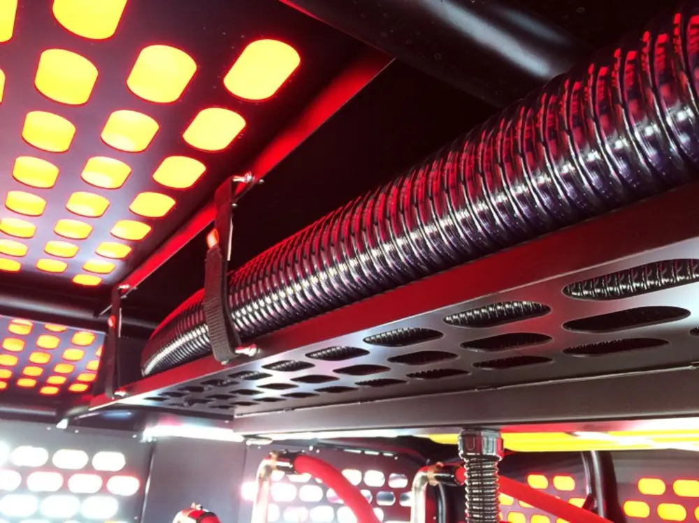 Exterior view of small fire truck showing cab, body compartments, and wheel/tire area.