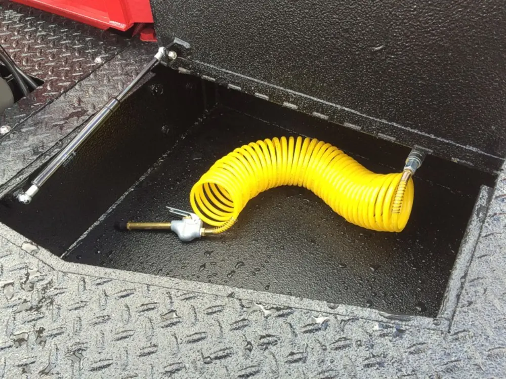 Exterior view of small fire truck showing cab, body compartments, and wheel/tire area.