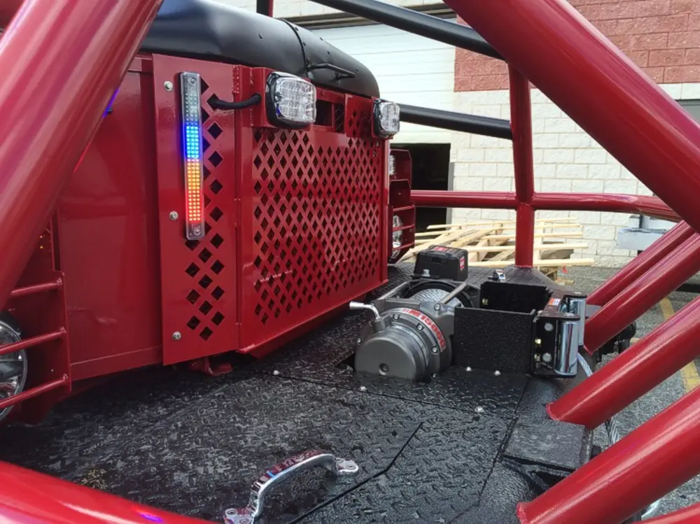 Exterior view of small fire truck showing cab, body compartments, and wheel/tire area.