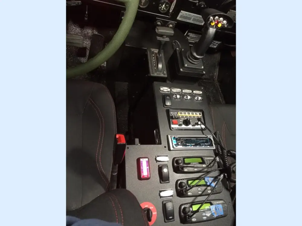 Exterior view of small fire truck showing cab, body compartments, and wheel/tire area.