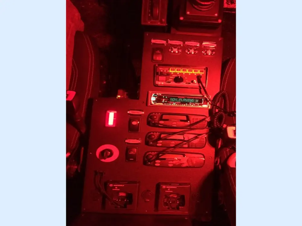 Exterior view of small fire truck showing cab, body compartments, and wheel/tire area.