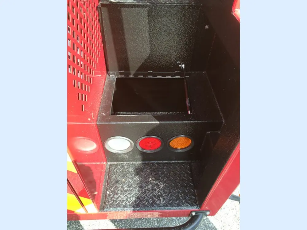 Exterior view of small fire truck showing cab, body compartments, and wheel/tire area.
