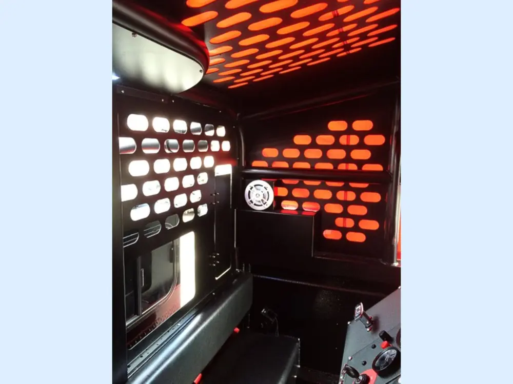 Exterior view of small fire truck showing cab, body compartments, and wheel/tire area.