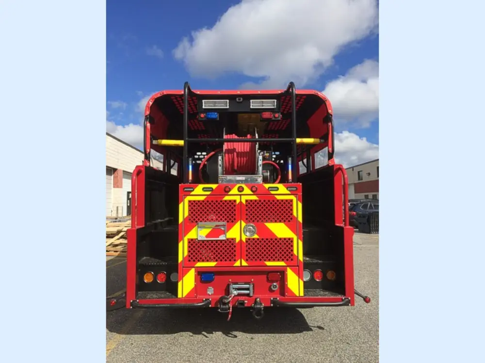 Exterior view of small fire truck showing cab, body compartments, and wheel/tire area.