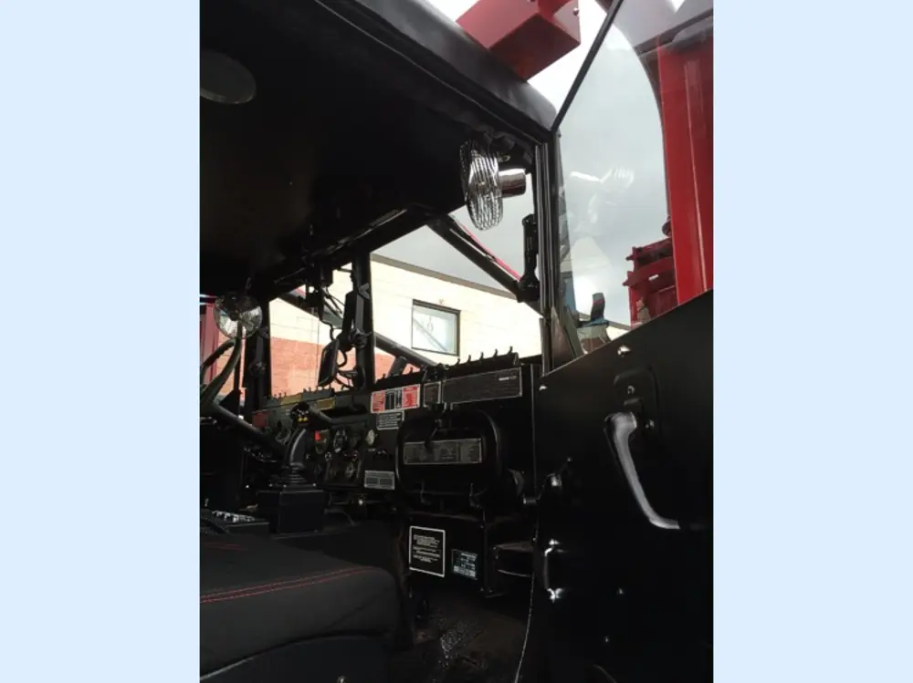 Exterior view of small fire truck showing cab, body compartments, and wheel/tire area.