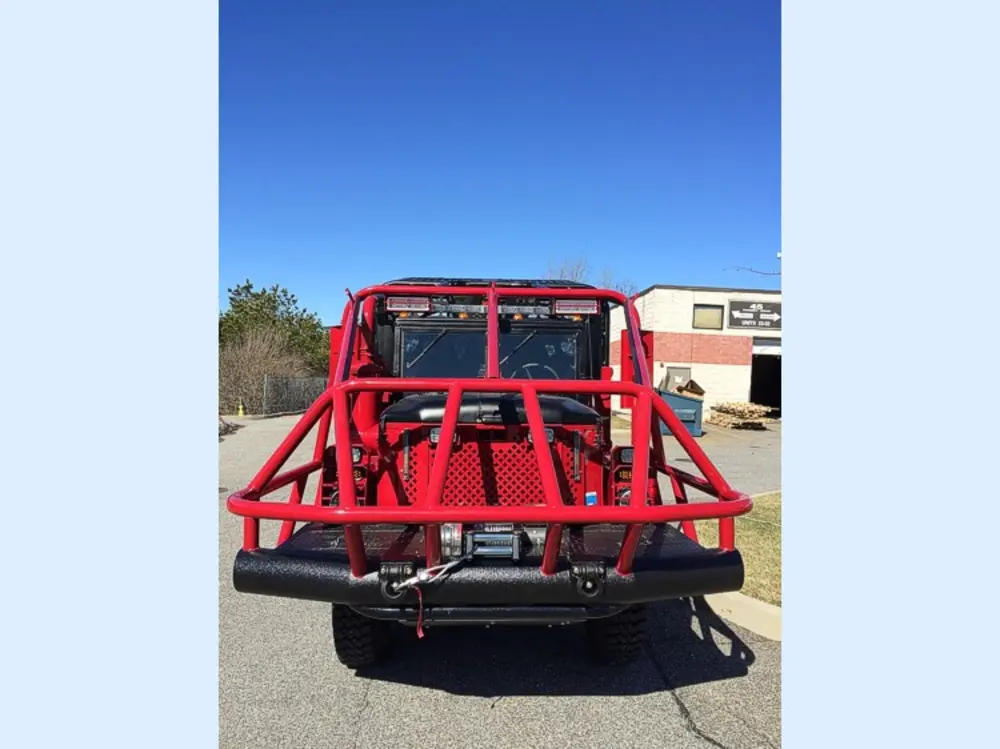 Exterior view of small fire truck showing cab, body compartments, and wheel/tire area.