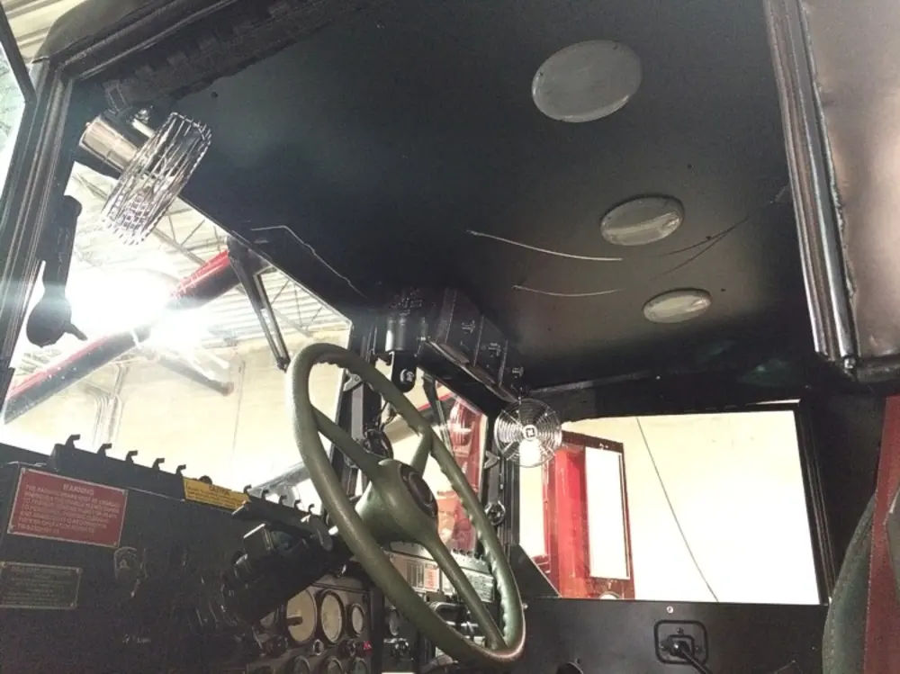 Exterior view of small fire truck showing cab, body compartments, and wheel/tire area.