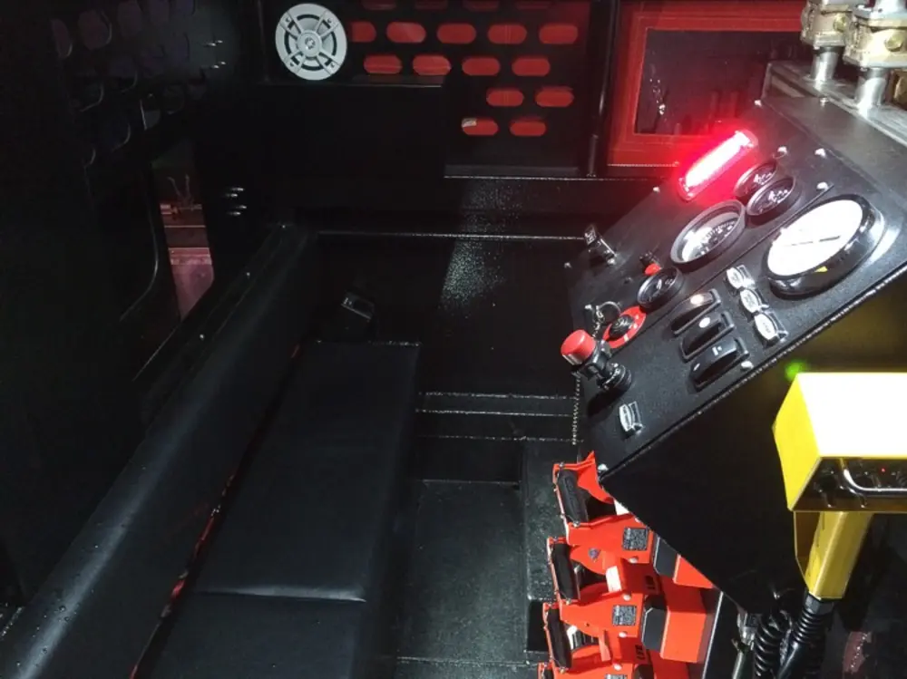 Exterior view of small fire truck showing cab, body compartments, and wheel/tire area.