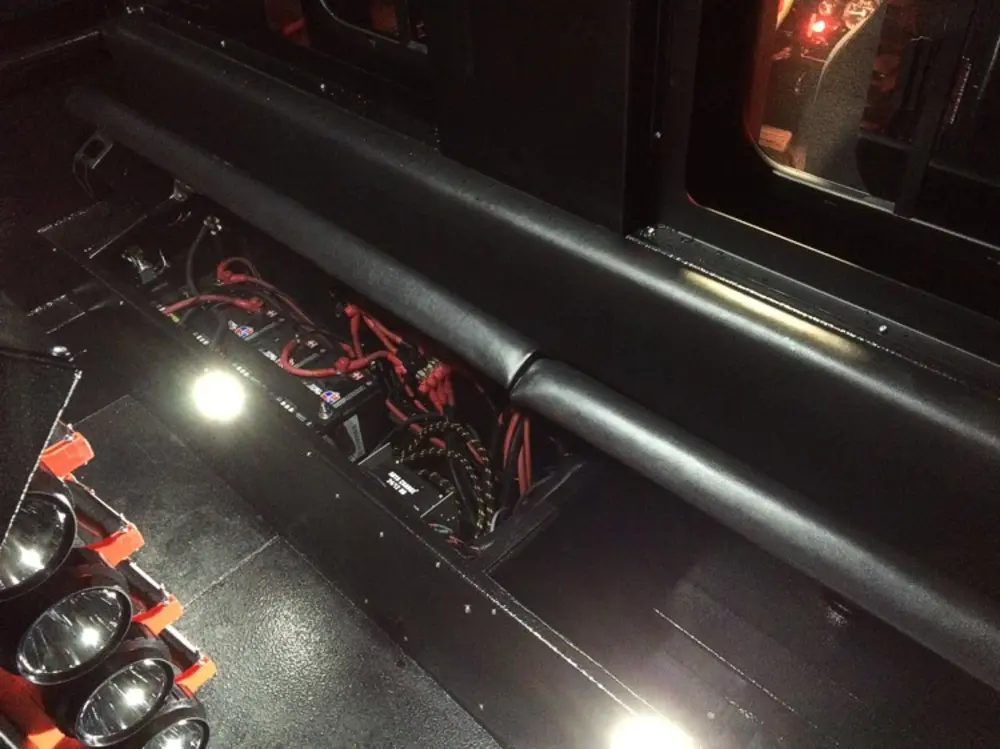 Exterior view of small fire truck showing cab, body compartments, and wheel/tire area.