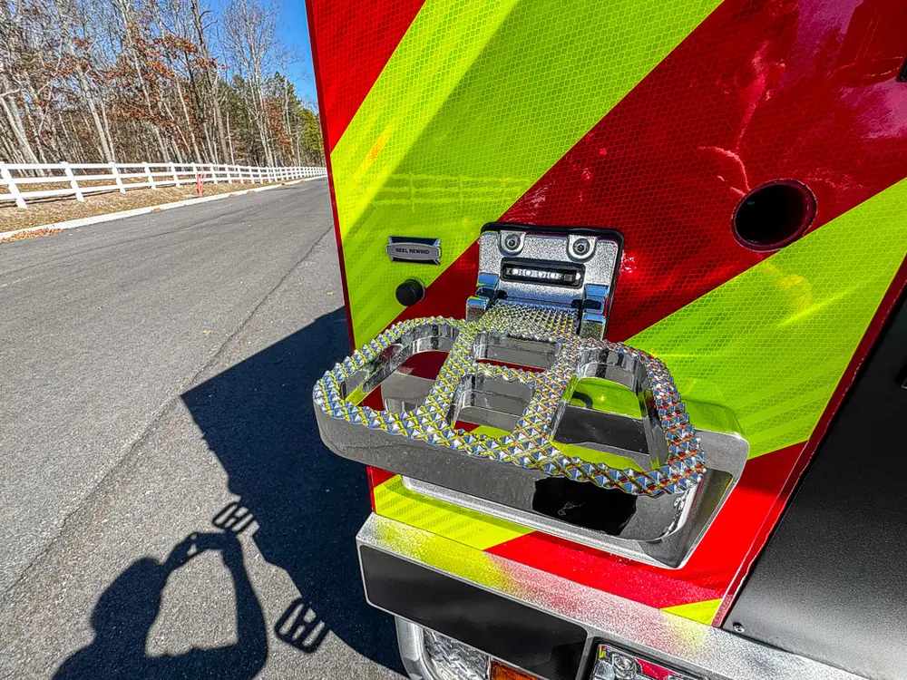 Rear corner close-up with fold-out step and mounted plate light.