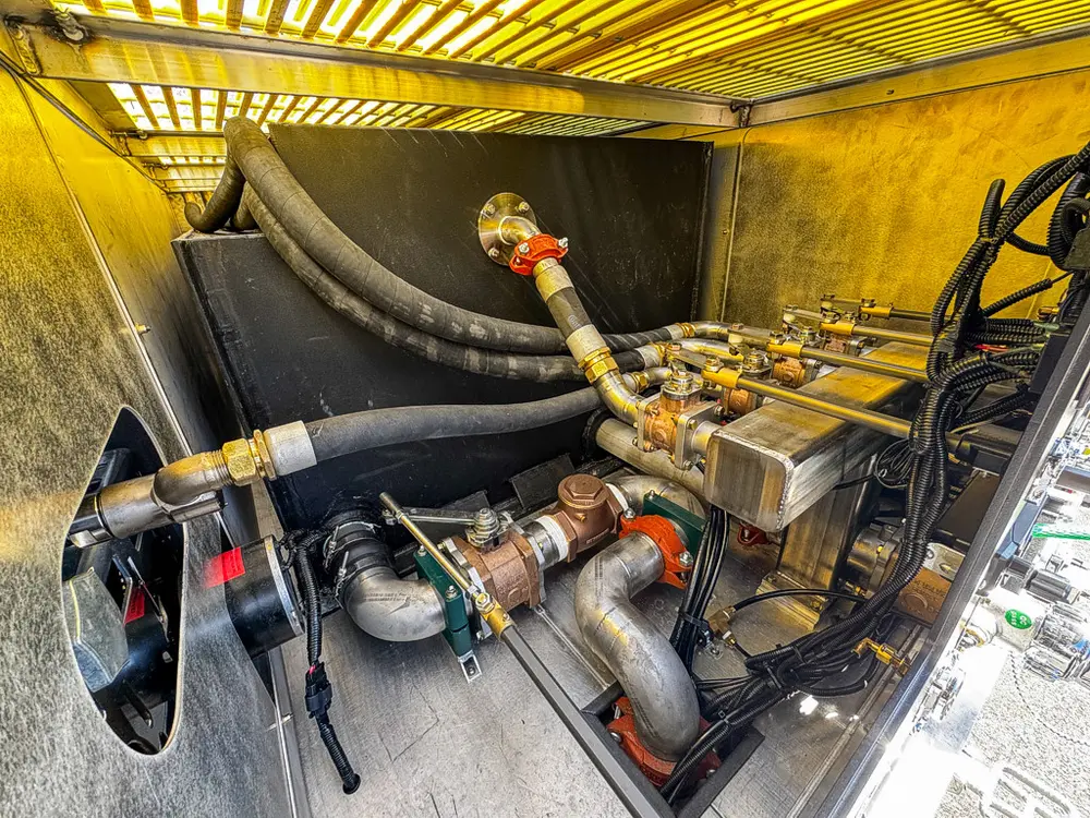 Pump compartment interior close-up with hoses, valves, and fittings.
