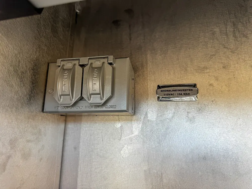 Compartment wall close-up with dual outlet and identification plate.