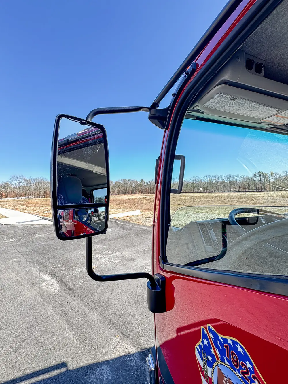 Driver-side mirror close-up against the open roadway background.