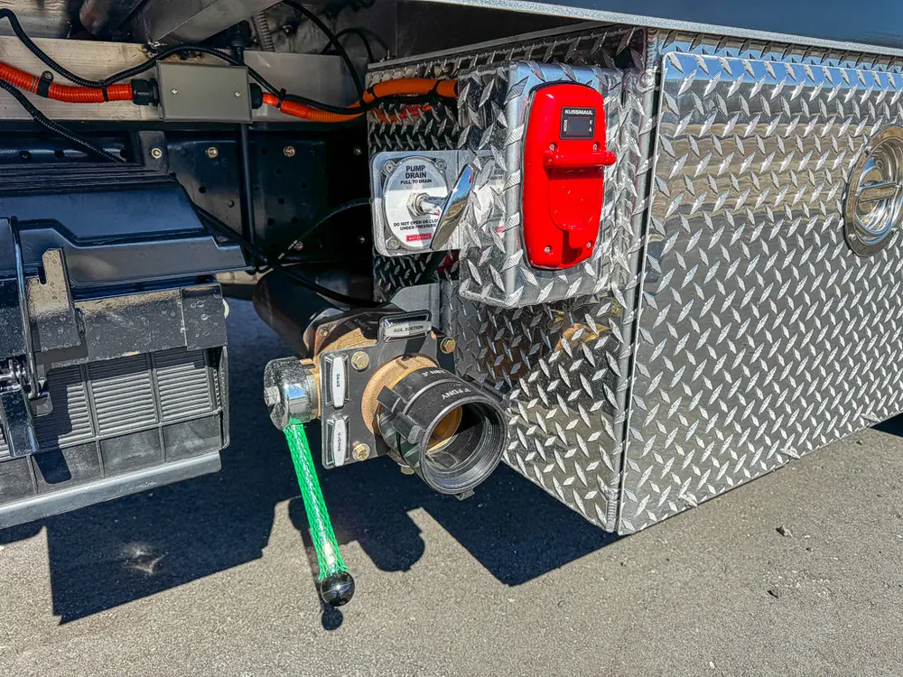 Side pump plumbing close-up with intake valve and red outlet cover.
