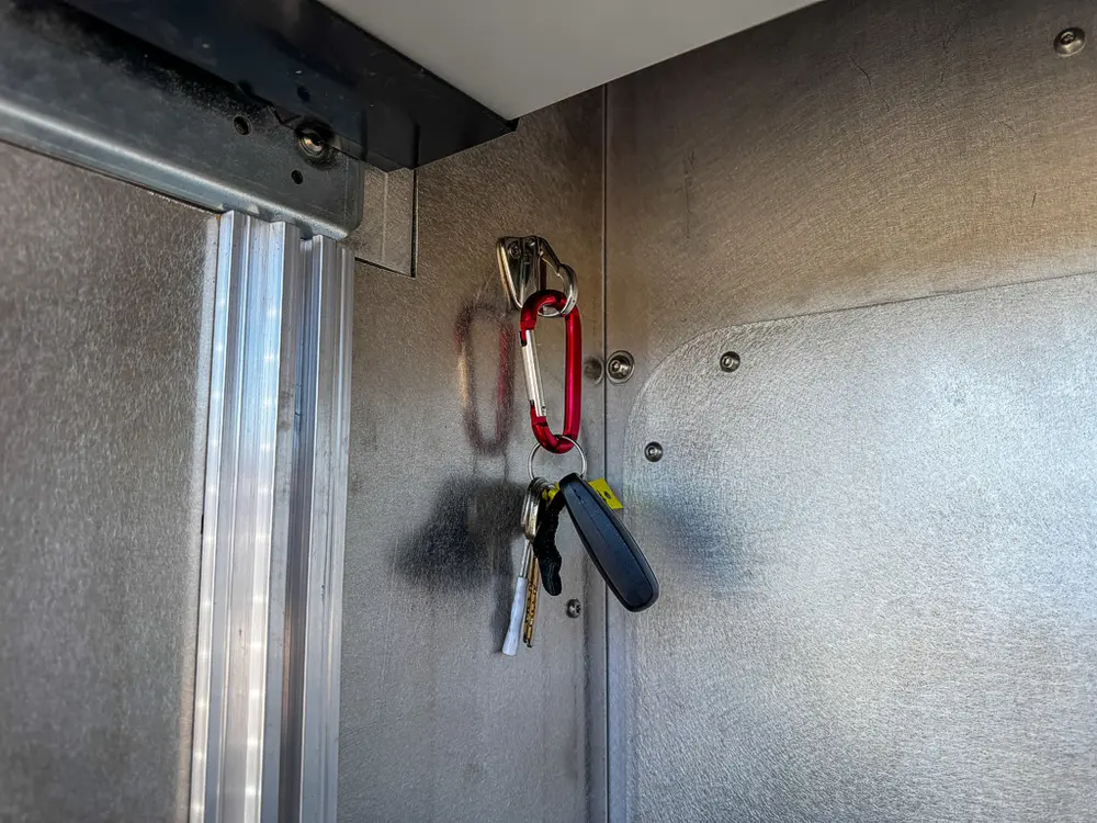 Compartment interior close-up with wall-mounted hooks and clips.