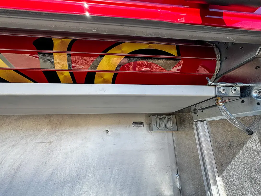 Upper shelf underside and mounted red cylinder inside a compartment.