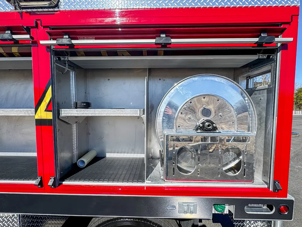 Open side compartment with mounted hose reel and shelf.