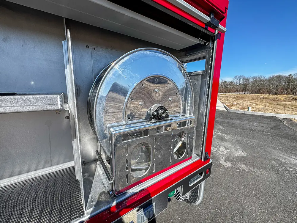 Open side compartment showing mounted hose reel and metal divider.