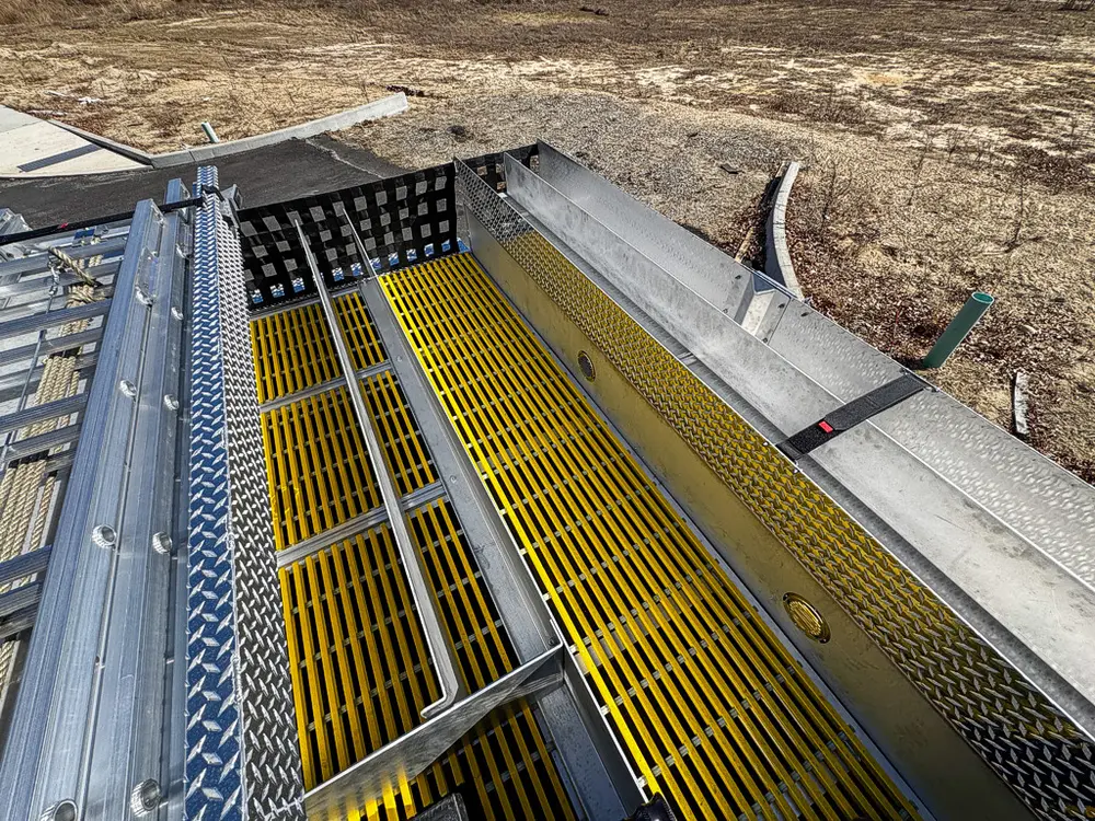 Top walkway view toward rear with yellow grating and side rails.