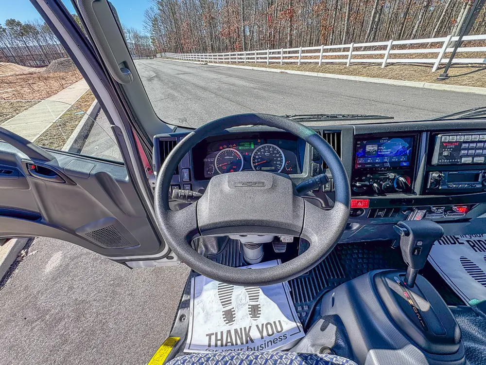 Driver cockpit close-up with steering wheel and instrument cluster.